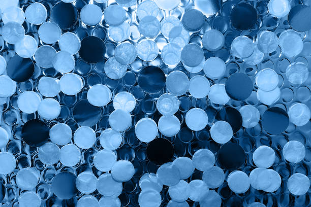 istock Confetti on shiny blue foil surface with round impressions for textured background. 1192890307