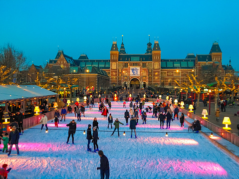 People skating on an ice ring in front of the Rijksmuseum in Amsterdam, the capital of The Netherlands during a beautiful cold winter evening.