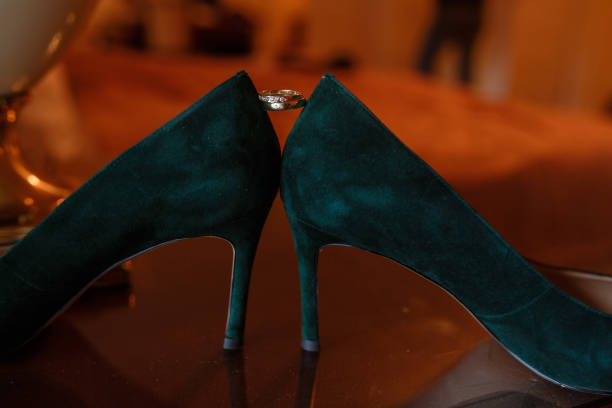 Green Wedding shoes and gold rings on the table in room, accessories bride on the wedding day in warm colors