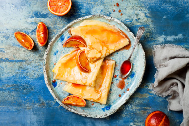 hausgemachte crepes pfannkuchen in keramikplatte mit orangensauce serviert. französische crepe suzette mit blutigem orangensirup. - pancake blini russian cuisine french cuisine stock-fotos und bilder