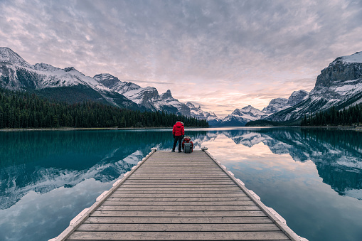 Couple traveler relaxing on wooden pier in Maligne lake at Spirit island, Jasper national park, Canada