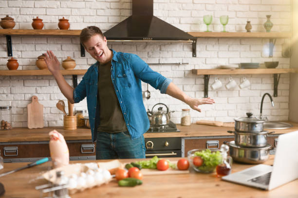 istock young handsome happy man dancing in well-equipped modern kitchen while cooking tasty breakfast , sunday morning 1192895117
