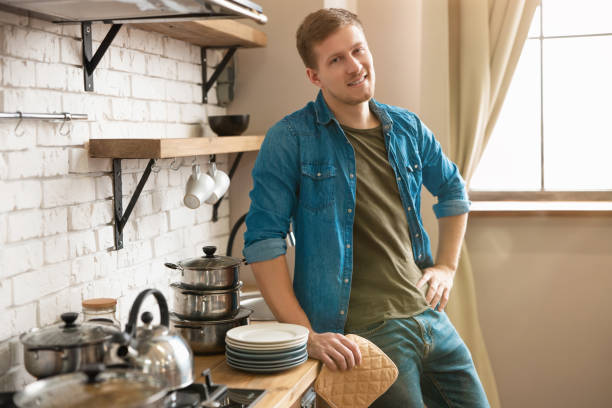 istock young smiling man standing in bright well-equipped modern kitchen looking satisfied after washing the dishes , bachelor life 1192895142
