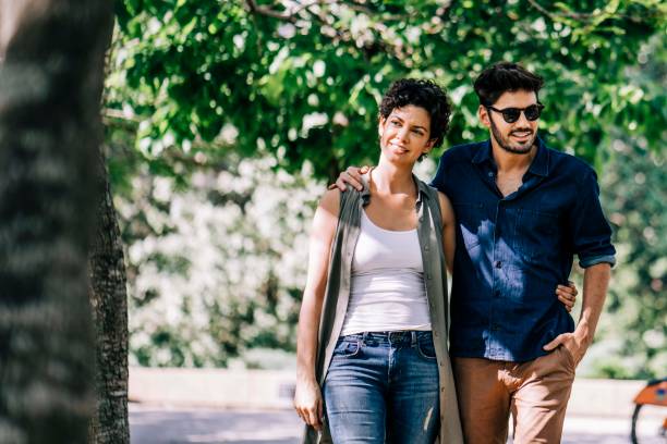 istock Smiling couple walking with arms around in park 1192895759
