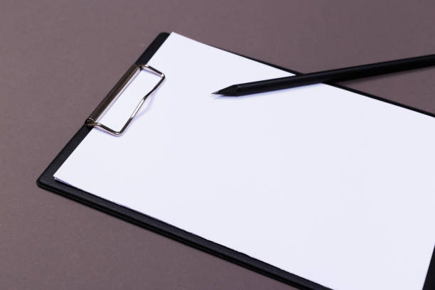 istock Clipboard with white sheet and pen on a colored background. View from above. space for text 1192897756