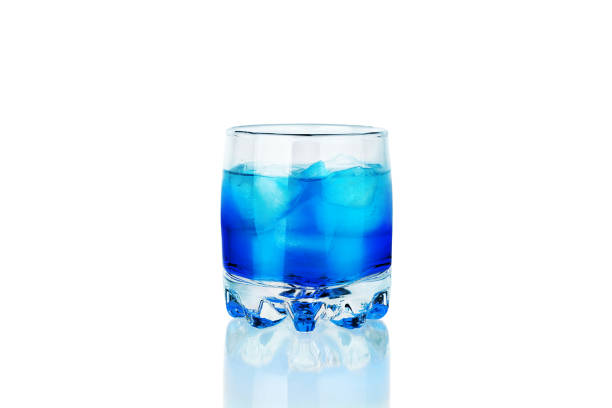 um copo da bebida azul do álcool com cubos de gelo e reflexão no close up isolado do fundo branco, cocktail azul da lagoa, tiro do absinto, sambuсa, licor azul do сuracao, bebida fria abstrata da cor de néon - blue transparent cold cube - fotografias e filmes do acervo