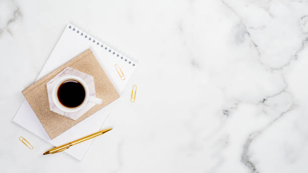 istock Flatlay white marble desk with office supplies, paper notepad and coffee cup. Top view with copy space. Elegant feminine workspace concept 1192900009