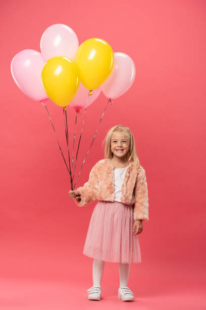 istock cute and smiling kid holding balloons on pink background 1192901071