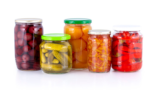 Pickled peach, apricot, cherry, cucumber, lecho (lecso), cowhorn chili peppers compote isolated on white with shadow reflection clipping path. Preserved,bottled,stewed fruits & vegetables in glass jar