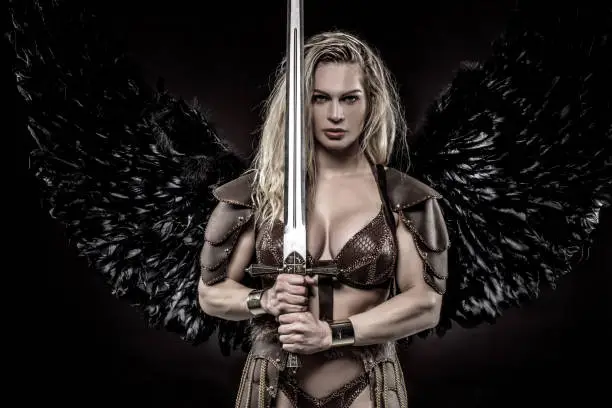 Black Wing Viking Valkyrie young blond female wielding a sword in a studio shot