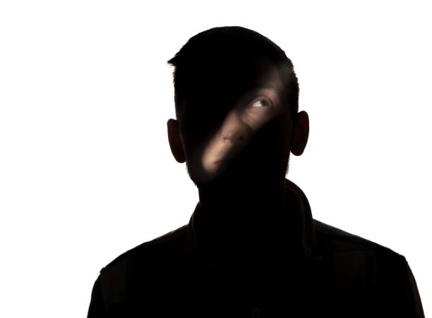 istock Dramatic portrait of a man in the dark on white studio background. 1192903744