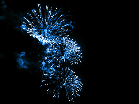 Close-up blue festive fireworks on a black background. Abstract holiday background
