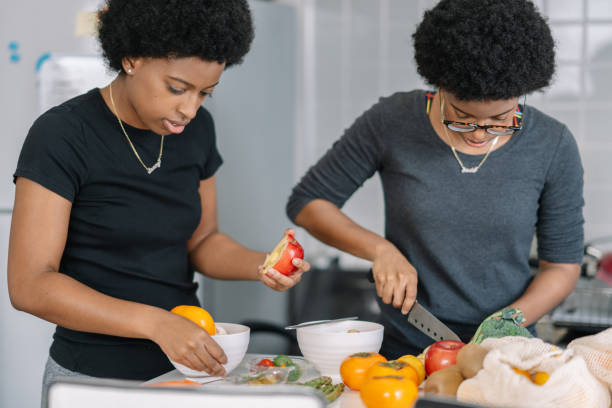 Young female twins preparing vegan food at home