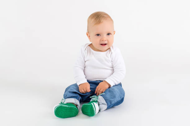 흰색 배경에 바닥에 앉아 귀여운 아이 - baby booties studio shot horizontal shoe 뉴스 사진 이미지