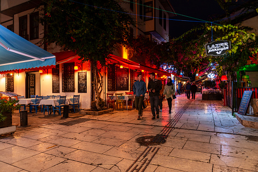 Antalya,Turkey - November 15, 2019: Empty restaurant tables and chairs in street of Kaleici, Antalya. Kaleici is the historic city center of Antalya. The narrow street is lined with outdoor terraces of the restaurants and bars. Kaleici district is the perfect place to choose souvenirs or go for the shopping, here locate a lot of stores, offering different goods.