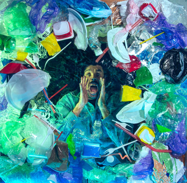 istock Man drowning in ocean water under plastic recipients pile, environment concept 1192906813
