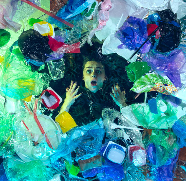 istock Woman drowning in ocean water under plastic recipients pile, environment concept 1192906869