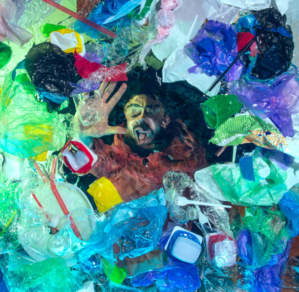 istock Man drowning in ocean water under plastic recipients pile, environment concept 1192906878