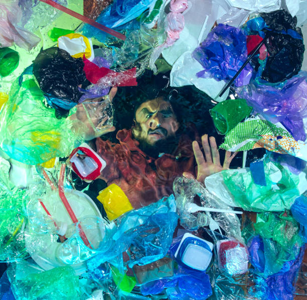 istock Man drowning in ocean water under plastic recipients pile, environment concept 1192906883