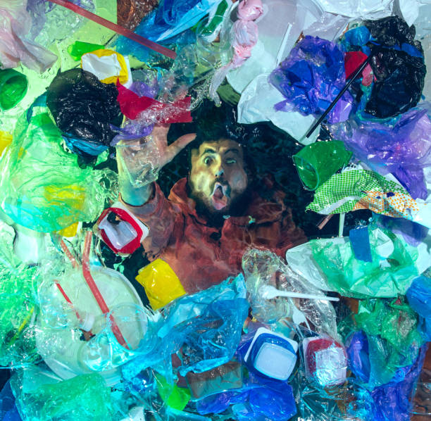 istock Man drowning in ocean water under plastic recipients pile, environment concept 1192906888