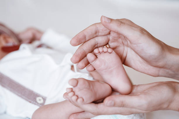 istock Newborn Baby's feet on female hands closeup. 1192907129