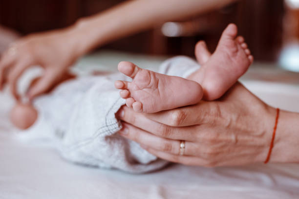 istock Newborn Baby's feet on female hands closeup. 1192907444