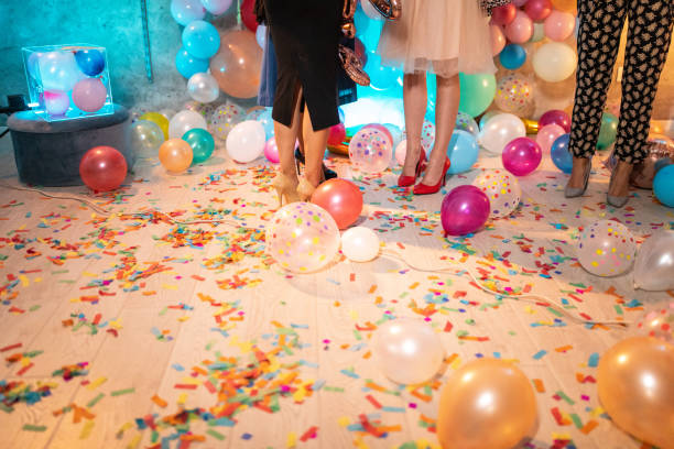 Who will clean this mess? Low section of well dressed female friends after party, with balloons and confetti on floor after party stock pictures, royalty-free photos & images