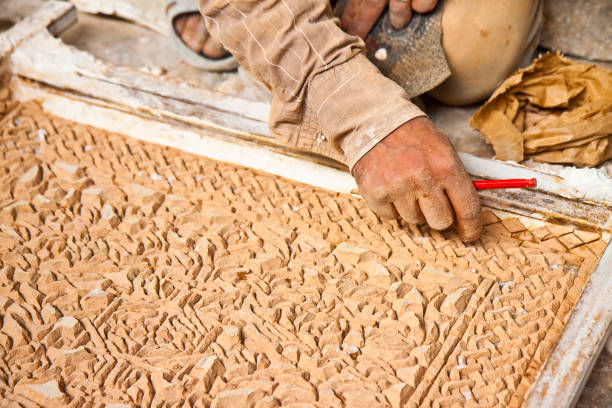 A young man is focused on working in his workshop, skillfully holding and inspecting an object. The setting exudes a hands-on, dedicated atmosphere that highlights craftsmanship and determination.