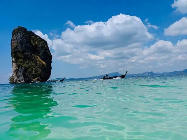 Aonang, Krabi / Thailand - February 11, 2019: Aonang Beach, the beautiful and famous place in Thailand, blue sky cloudy, mountain and green sea with long tail boats, good for the vacation season.