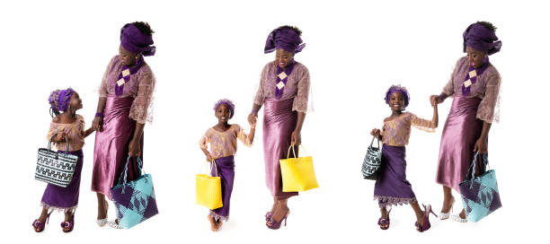 concept d'enfance et de famille - ensemble de femme africaine et de petite fille dans les vêtements pourpres traditionnels avec des sacs fourre-tout d'isolement - nigeria african culture dress smiling photos et images de collection