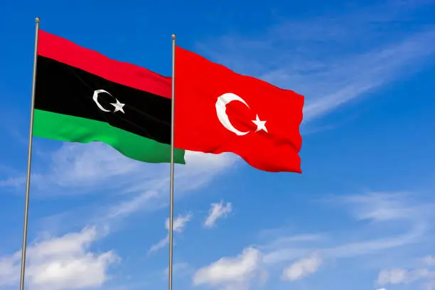 Libya and Turkey flags over blue sky background. 3D illustration