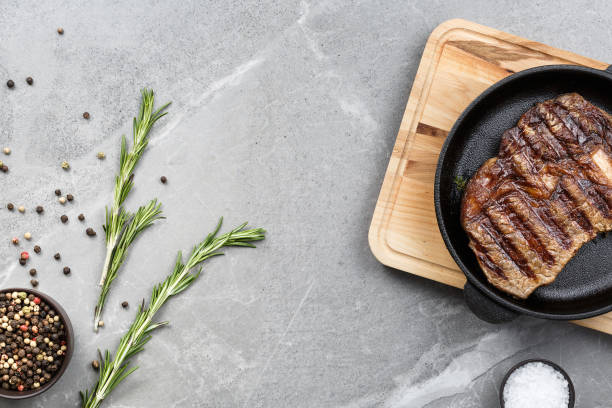 istock fried steak in pan on gray marble table top view 1192911842