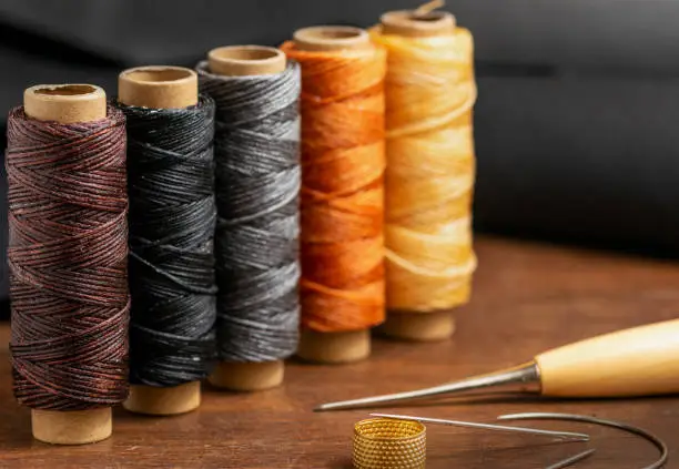 Sewing threads of brown, black, gray orange and yellow colors closeup