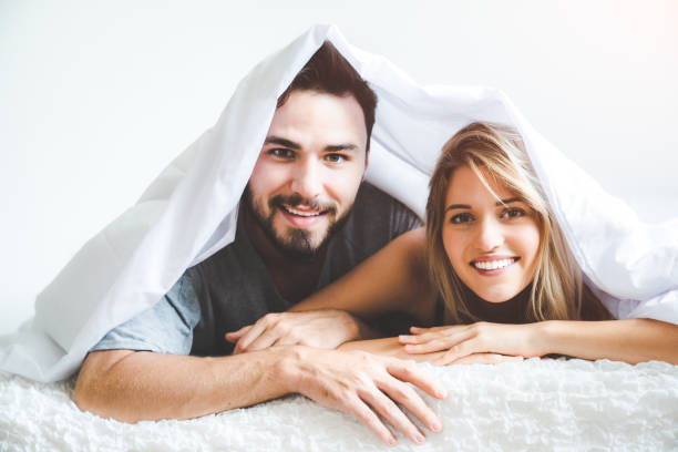 Happy young couple in bed and hugging stock photo
