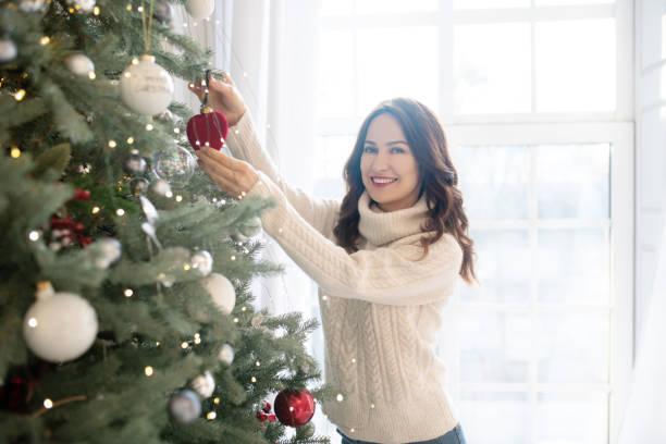 istock Young pretty smiling woman decorating christmas tree 1192914023