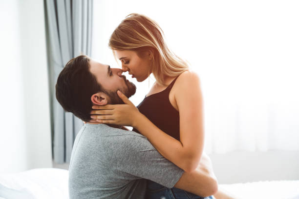 Cute couple relaxing on bed and kissing stock photo