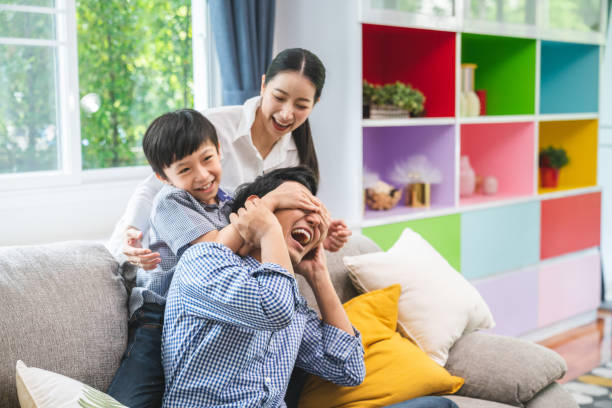 Son blindfolded cute father at home and kids laughing stock photo