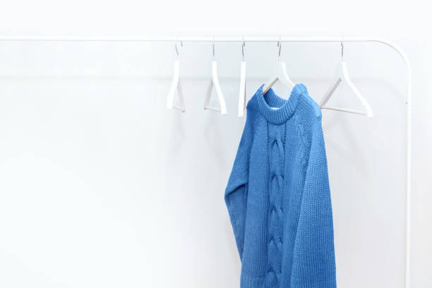 istock One classic blue knitted warm sweater on white hanger and many empty hangers. 1192916935