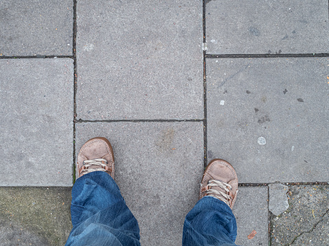 Grey concrete paving slabs with chewing gum and dirt, and pair of feet