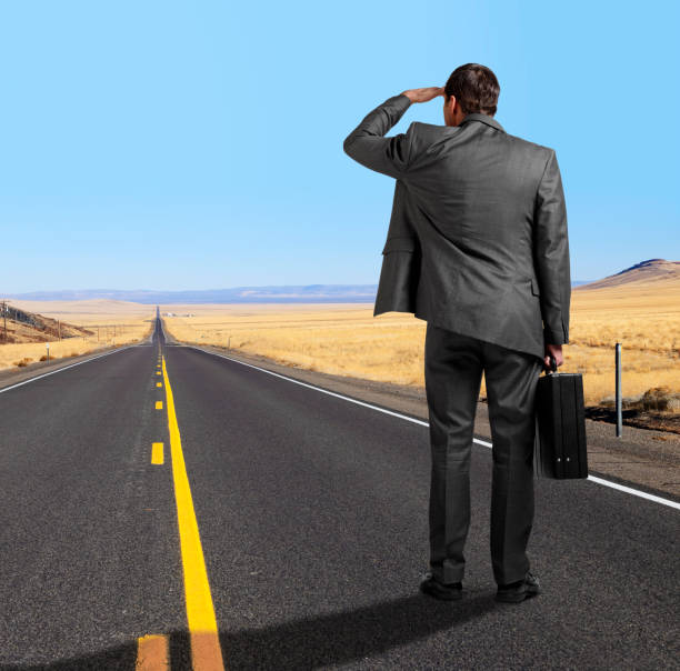 istock Businessman Looking Down Long Straight Rural Highway 1192929985