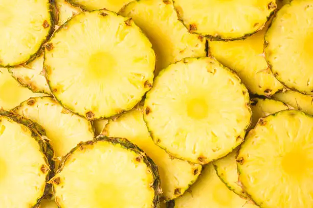 Photo of Pineapple juicy yellow slices background. Top view.
