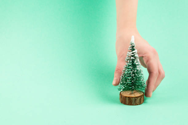 istock Small christmas tree in woman hand on a green background. 1192930111