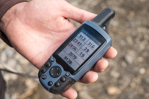 Old GPS tracker with distance and height information on its display lies in a mans hand