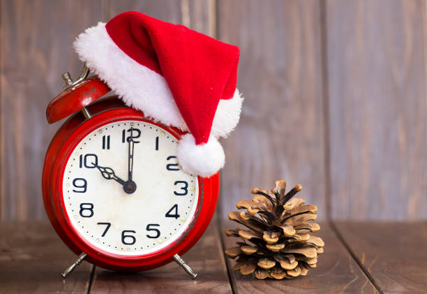 istock Christmas time. Red santa hat alarm clock and pine tree cone 1192932042