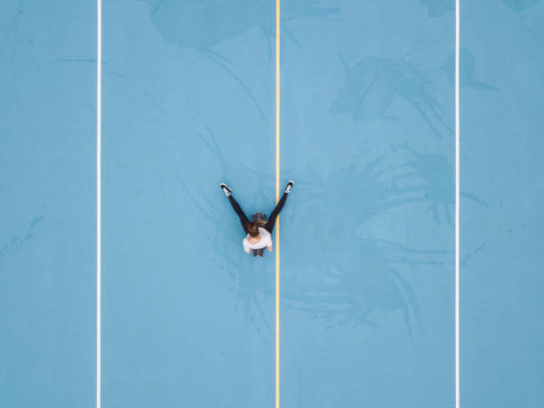 istock Woman sitting on skateboard in blue school yard 1192934989
