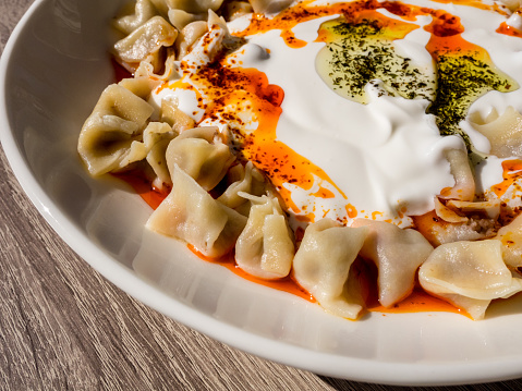 Manti turco con pimiento rojo, salsa de tomate, yogur y menta. Plato de comida tradicional turca. Vista superior photo