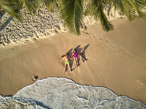 Family lying down on beach aerial top view drone shot at Seychelles, Mahe
