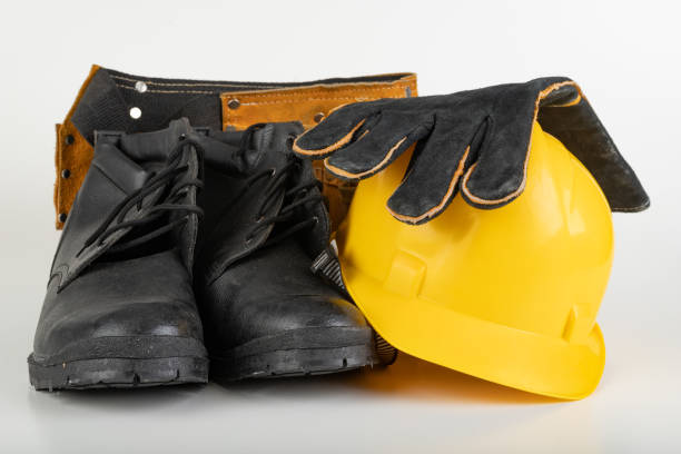 istock Helmet, work boots and gloves on a white table. Workwear for the production worker. Light background. 1192942540