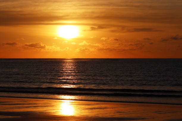 istock Sunset on a sandy beach, evening sea background, orange sun is reflected in dramatic waves 1192943290