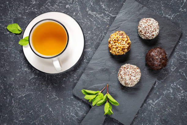 istock Hot tea cup with mint and sweets on black stone background 1192944576